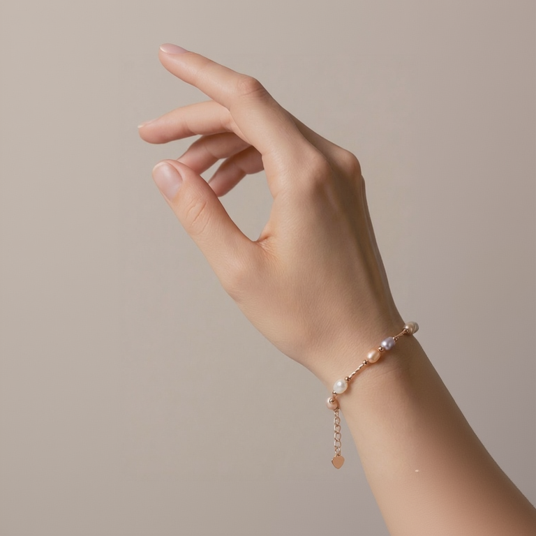 Hand wearing a delicate bracelet with pearls and rose gold accents on a neutral background