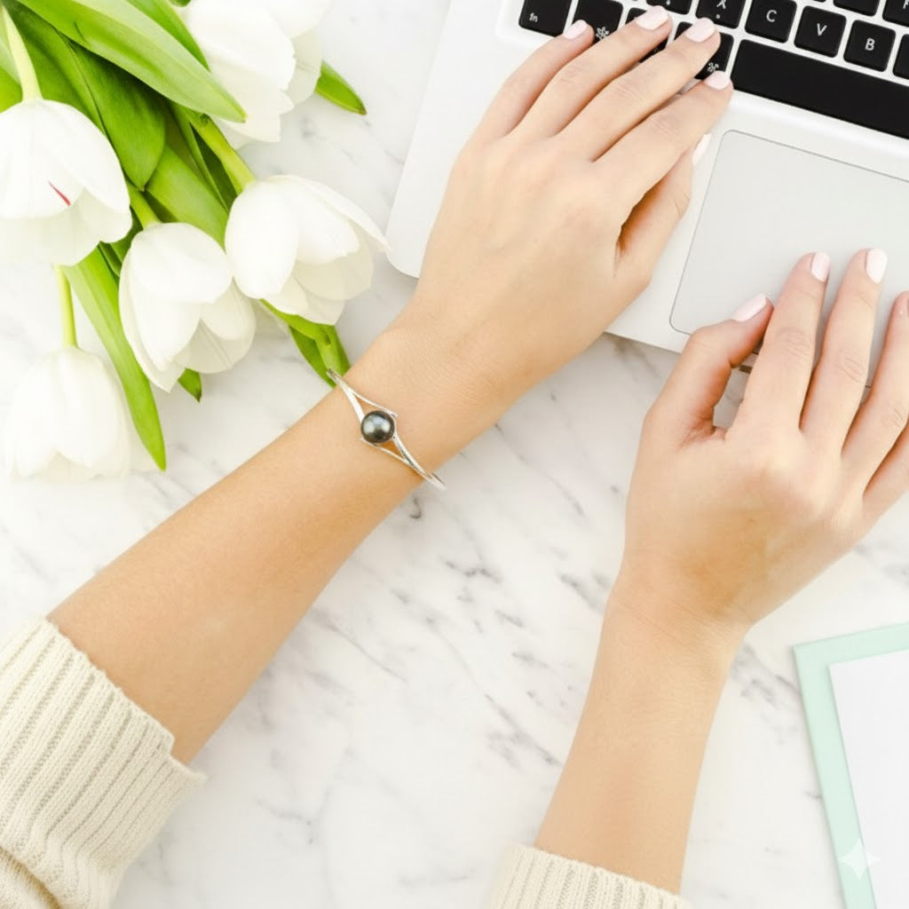 Hands typing on a laptop with white tulips on a marble surface