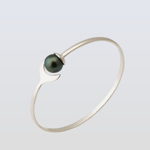 Silver bracelet with a dark green pearl on a light gray background