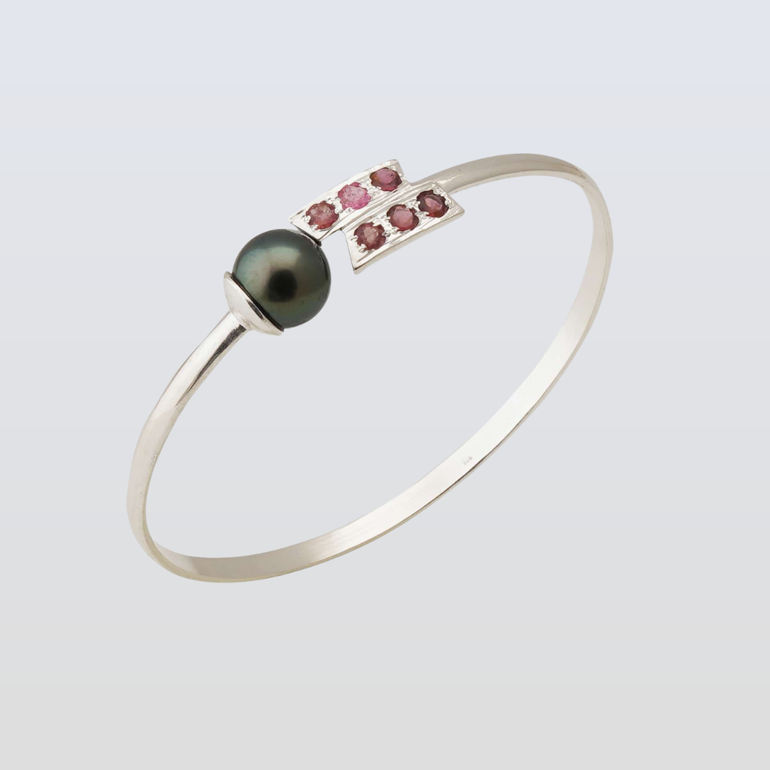 Silver bracelet with a black pearl and pink gemstones on a light gray background
