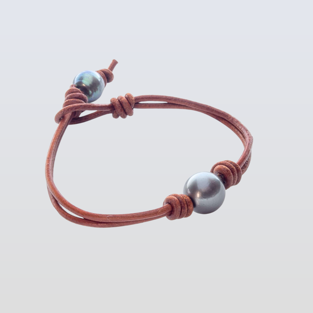 Bracelet with brown leather strap and silver beads on a light gray background
