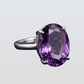 Silver ring with a large purple gemstone on a light gray background