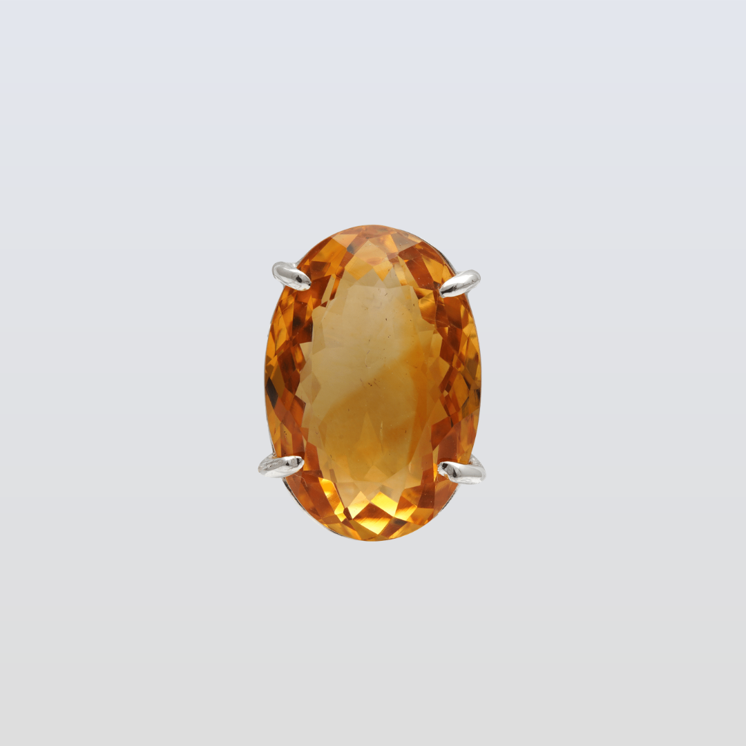 Gold pendant with a large orange gemstone on a light gray background