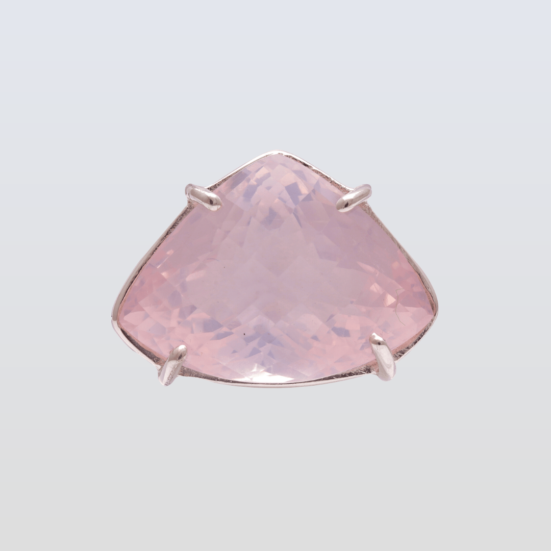 Pink gemstone ring with silver prongs on a light gray background