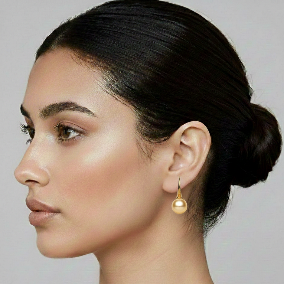 Close-up of a woman wearing a gold earring with a plain background