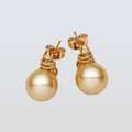 Gold pearl earrings on a light gray background