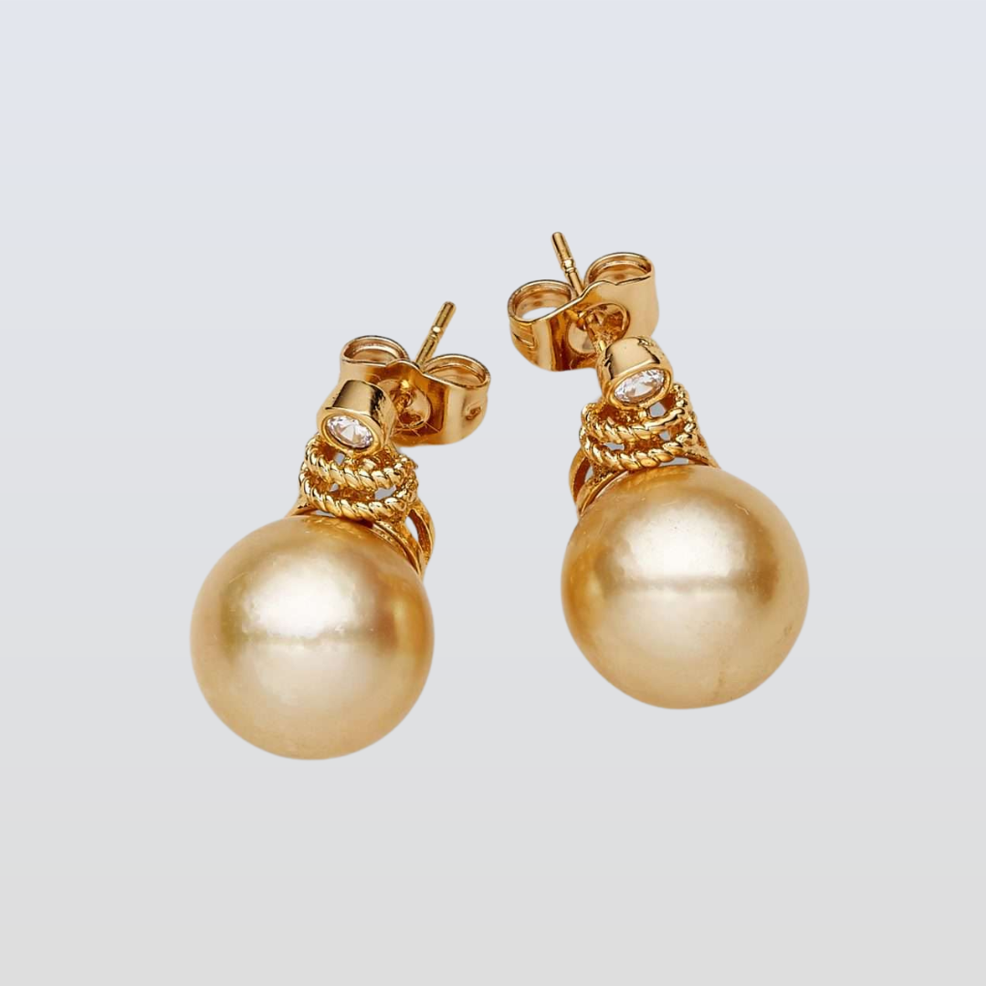 Gold pearl earrings on a light gray background