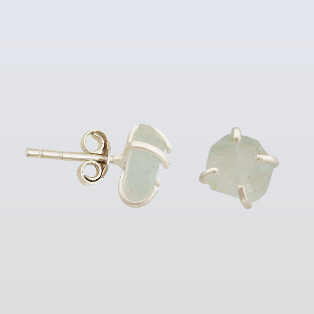Pair of light green stone earrings with gold posts on a light gray background