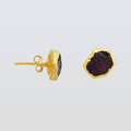 Gold earrings with purple gemstones on a light gray background