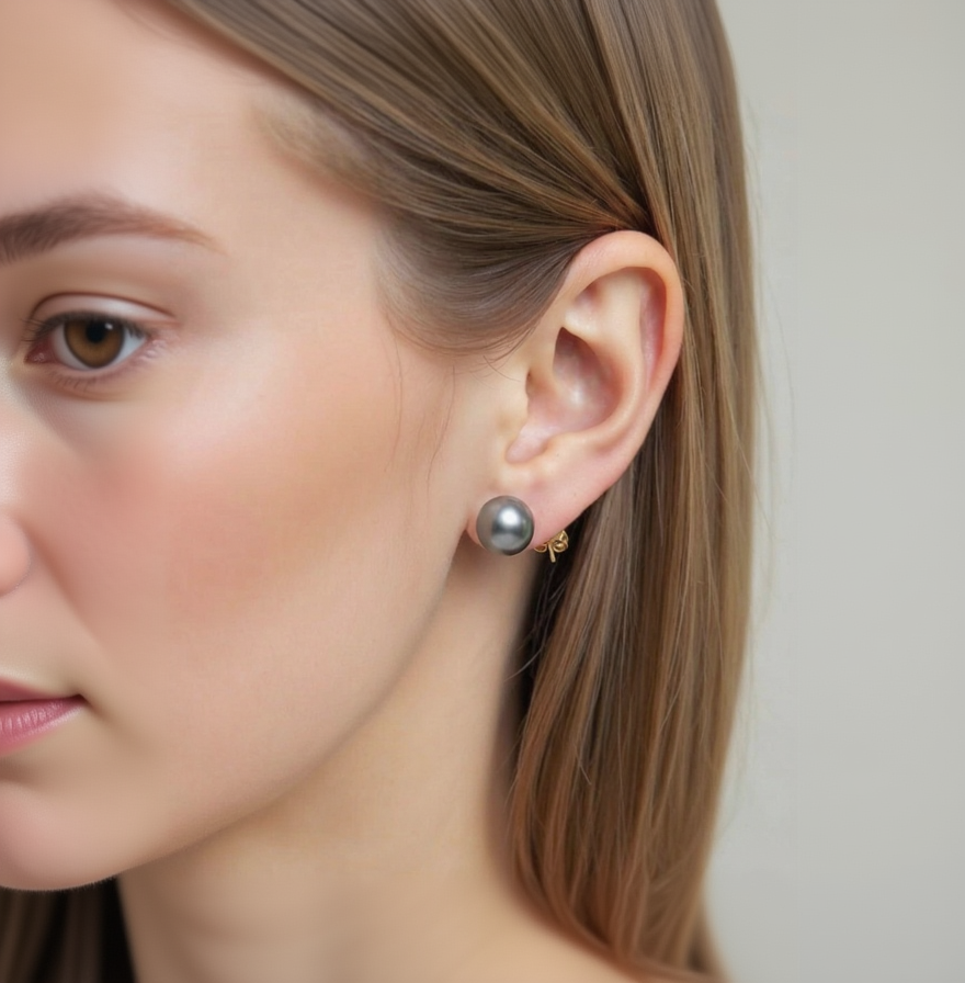 Close-up of a person wearing a black pearl earring with a gold backing.
