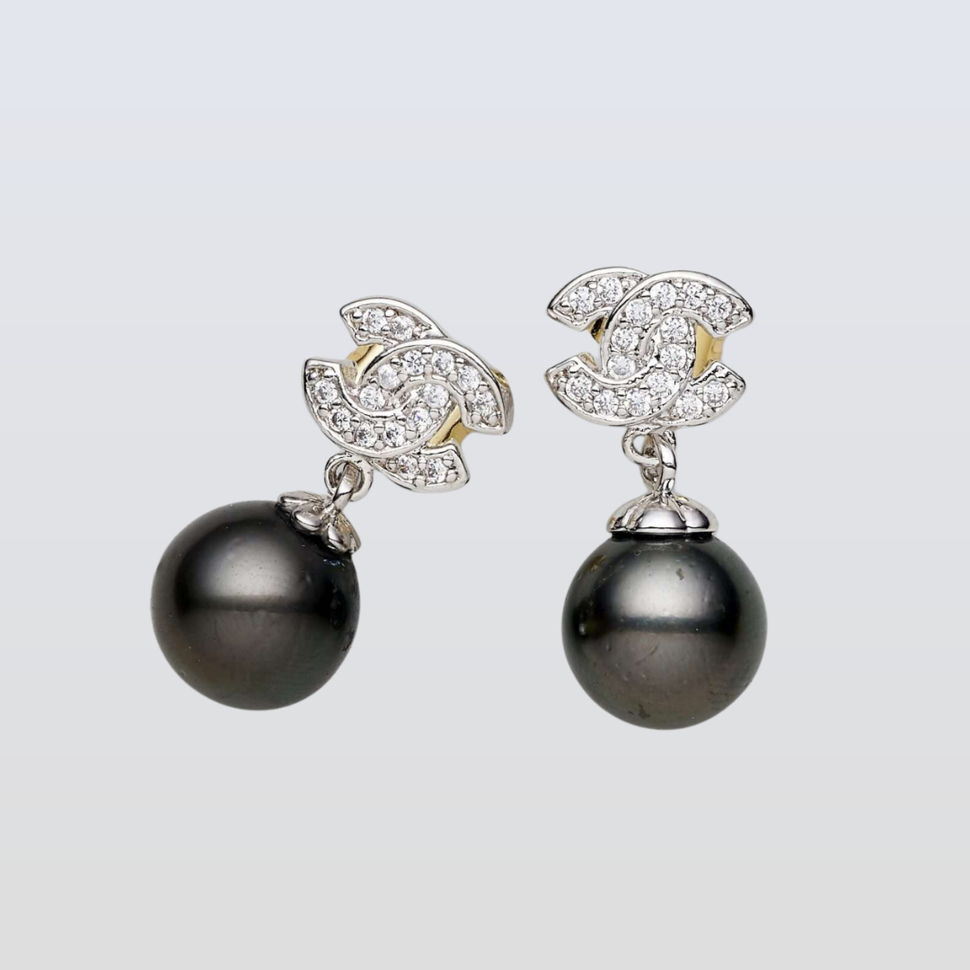 Pair of pearl earrings with diamond accents on a light gray background