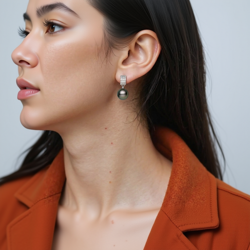 Close-up of a person wearing a silver earring with a dark bead.