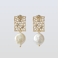 Gold earrings with pearl drops on a light gray background