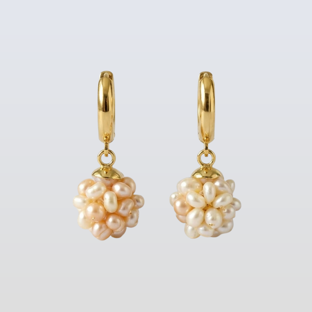 Gold earrings with pearl clusters on a light gray background