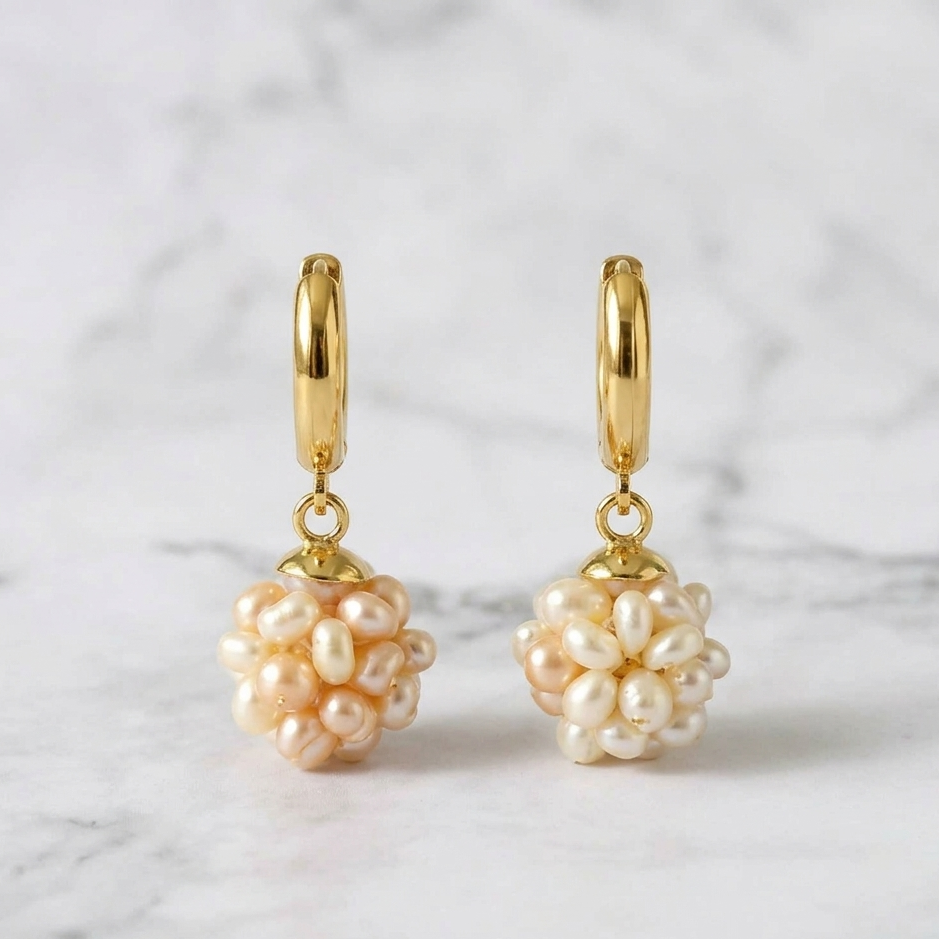 Gold hoop earrings with pearl drops on a marble background