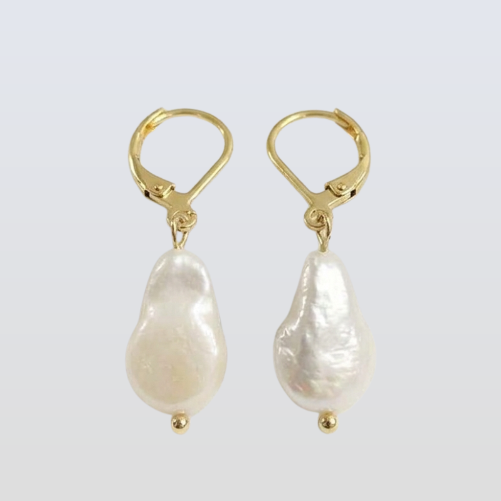 Gold earrings with white pearls on a light gray background
