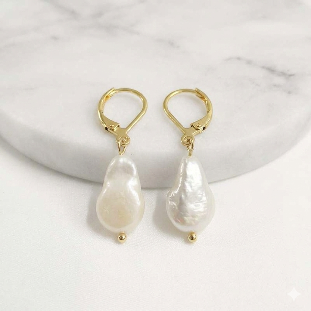 Gold earrings with white pearls on a marble surface
