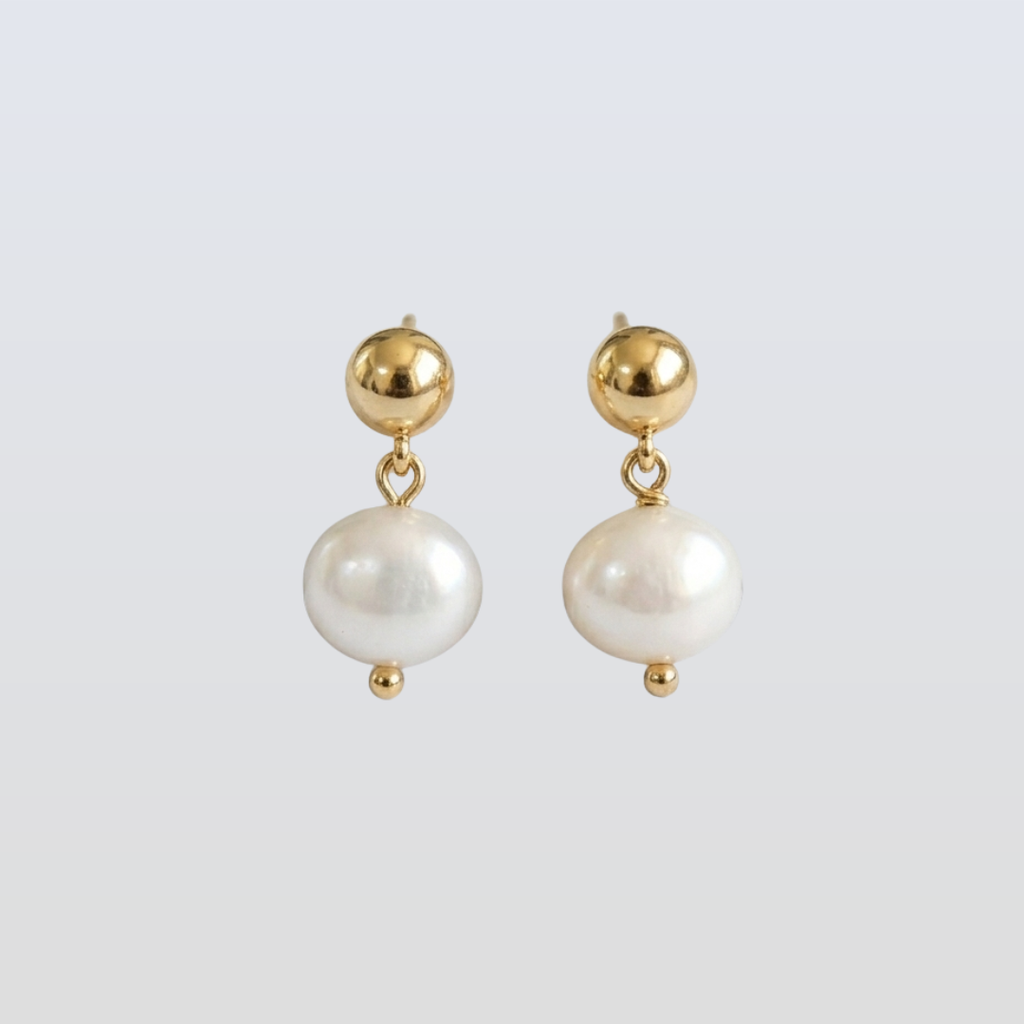 Pair of pearl earrings with gold accents on a light gray background