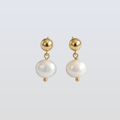 Pair of pearl earrings with gold accents on a light gray background