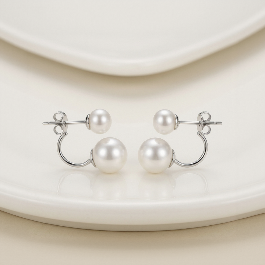 Pearl earrings with silver loops on a white plate