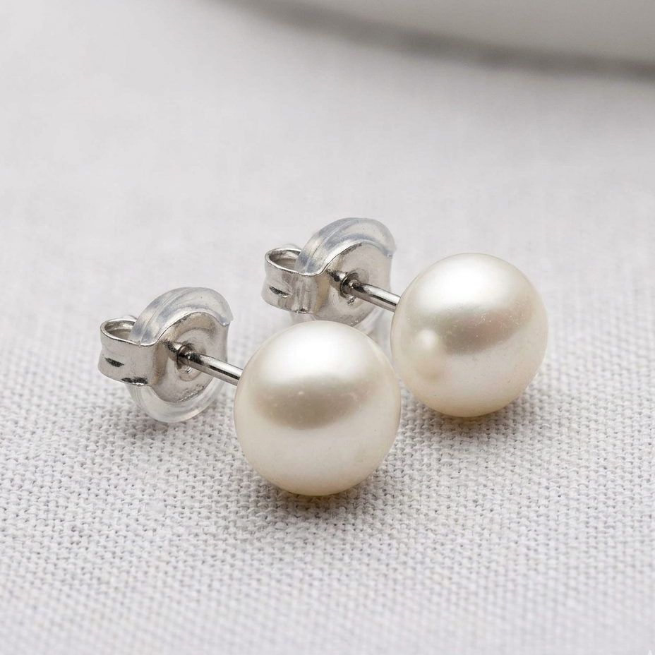 Pearl stud earrings on a light fabric background
