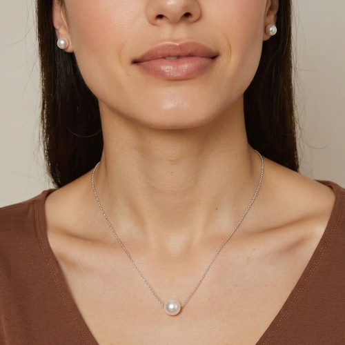 Woman wearing a pearl necklace and earrings against a neutral background