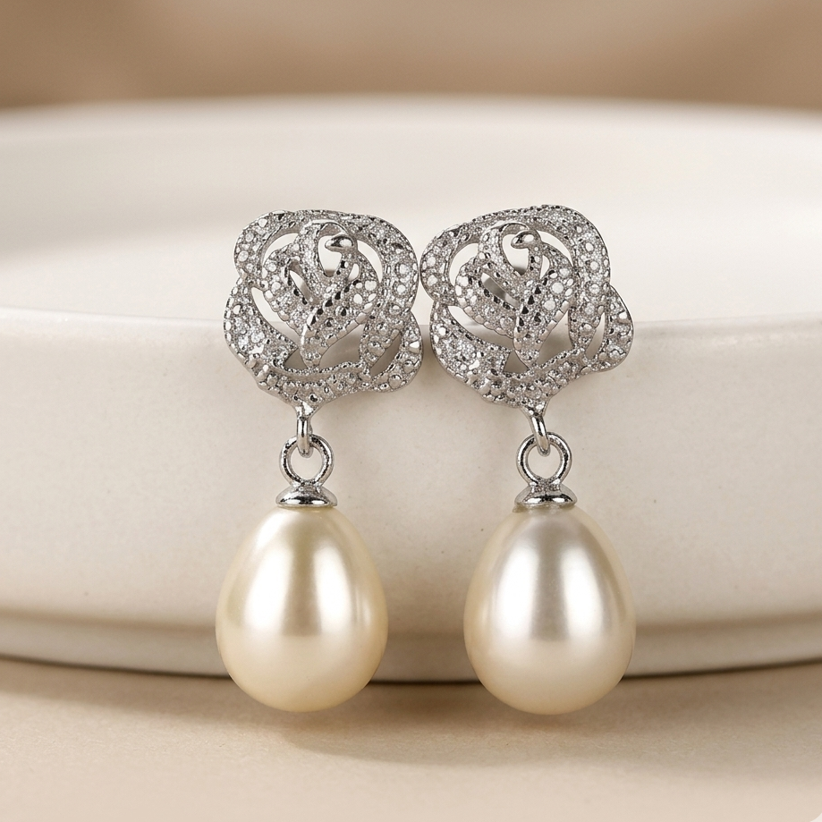 Pearl earrings with silver floral tops on a beige background