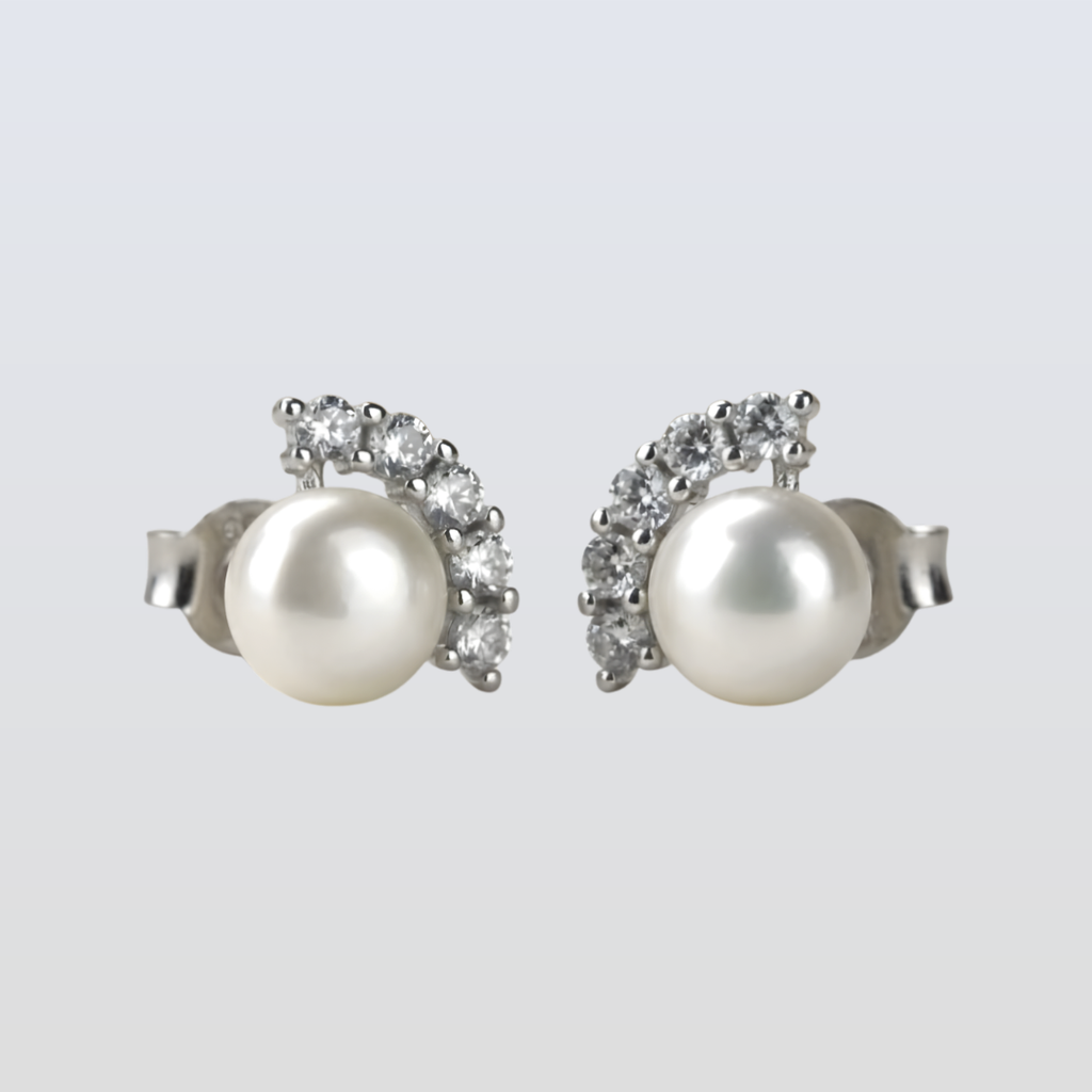 Pair of pearl earrings with silver and gemstone accents on a light gray background