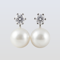 Pearl earrings with crystal tops on a light gray background