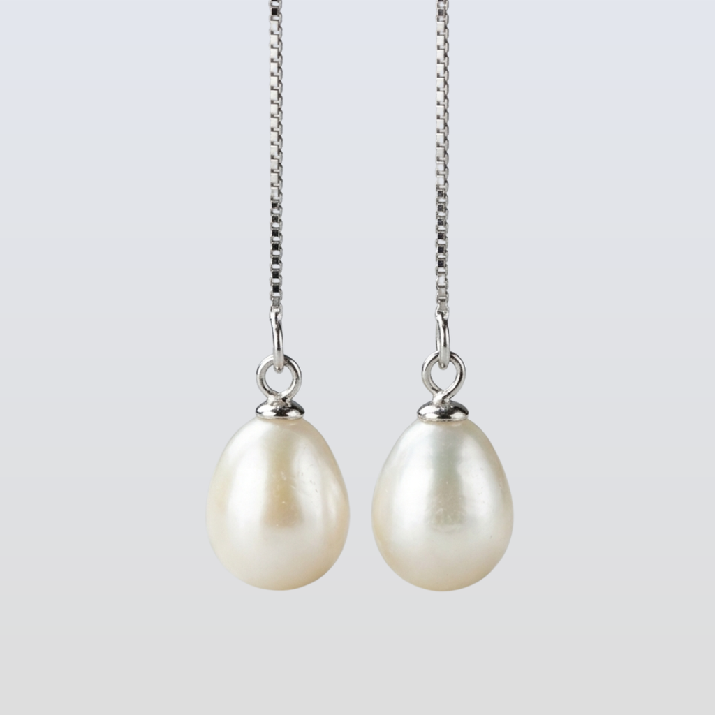 Pearl earrings on a silver chain against a light gray background