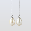 Pearl earrings on a silver chain against a light gray background