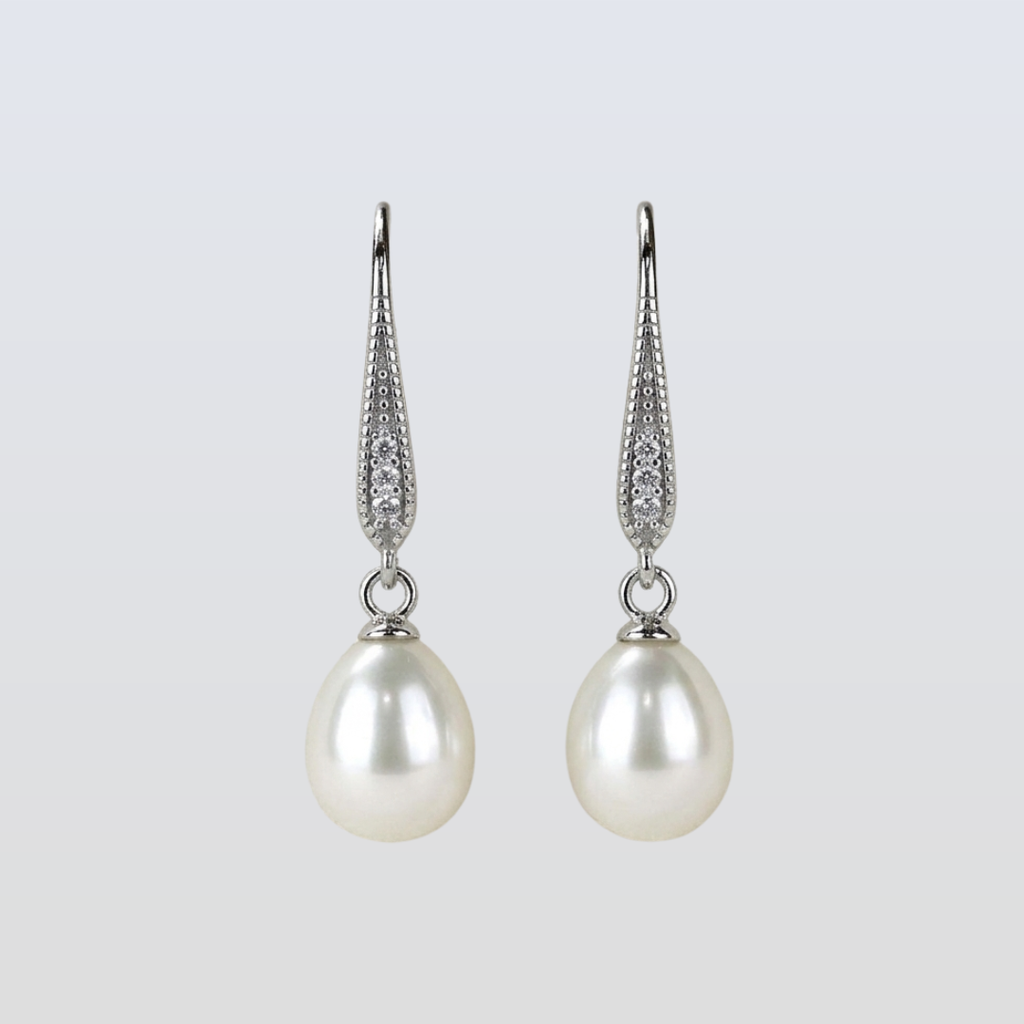 Pearl earrings with silver hooks on a light gray background