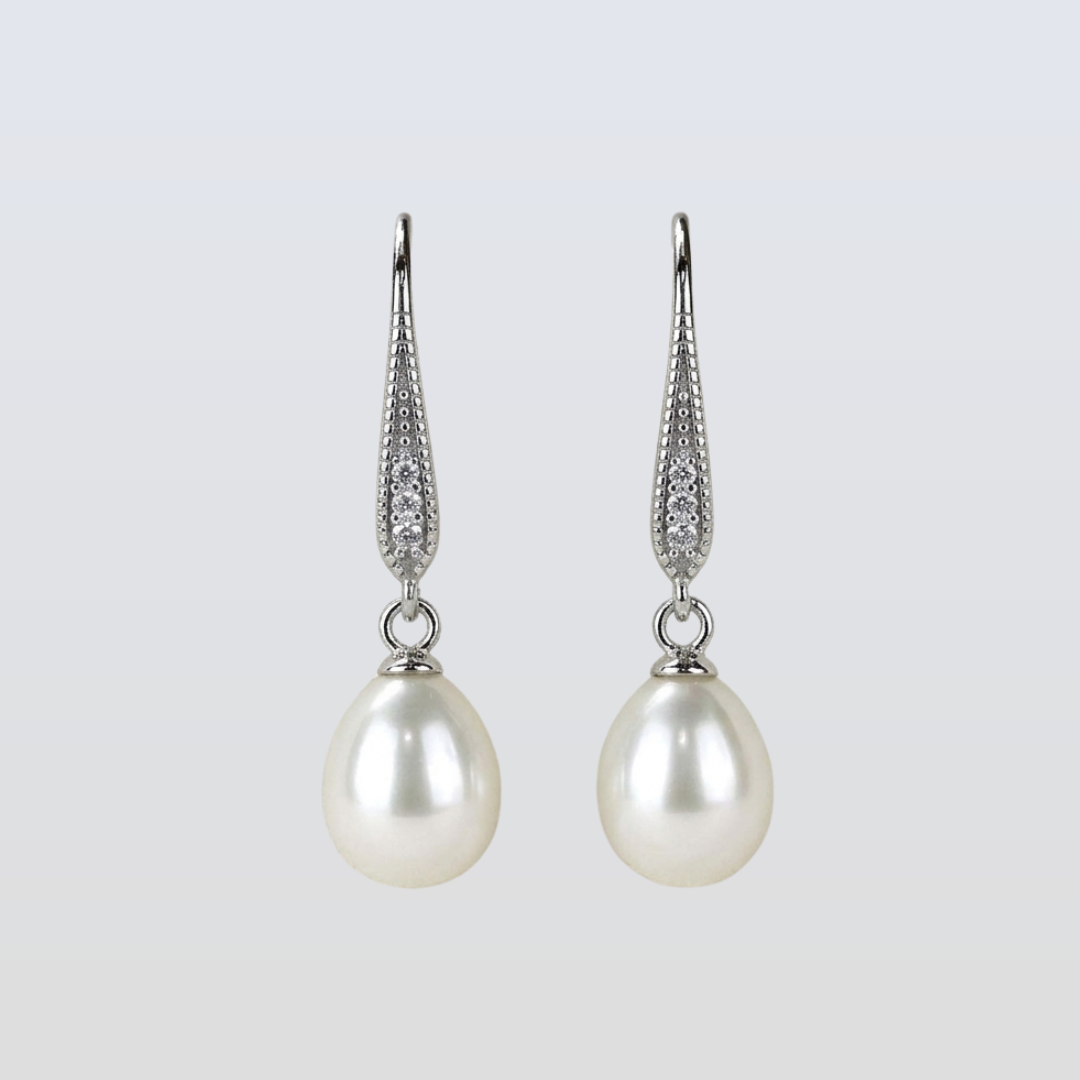 Pearl earrings with silver hooks on a light gray background