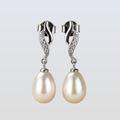 Pair of pearl earrings with silver clasps on a light gray background