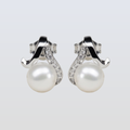 Pearl earrings with silver and diamond accents on a light gray background