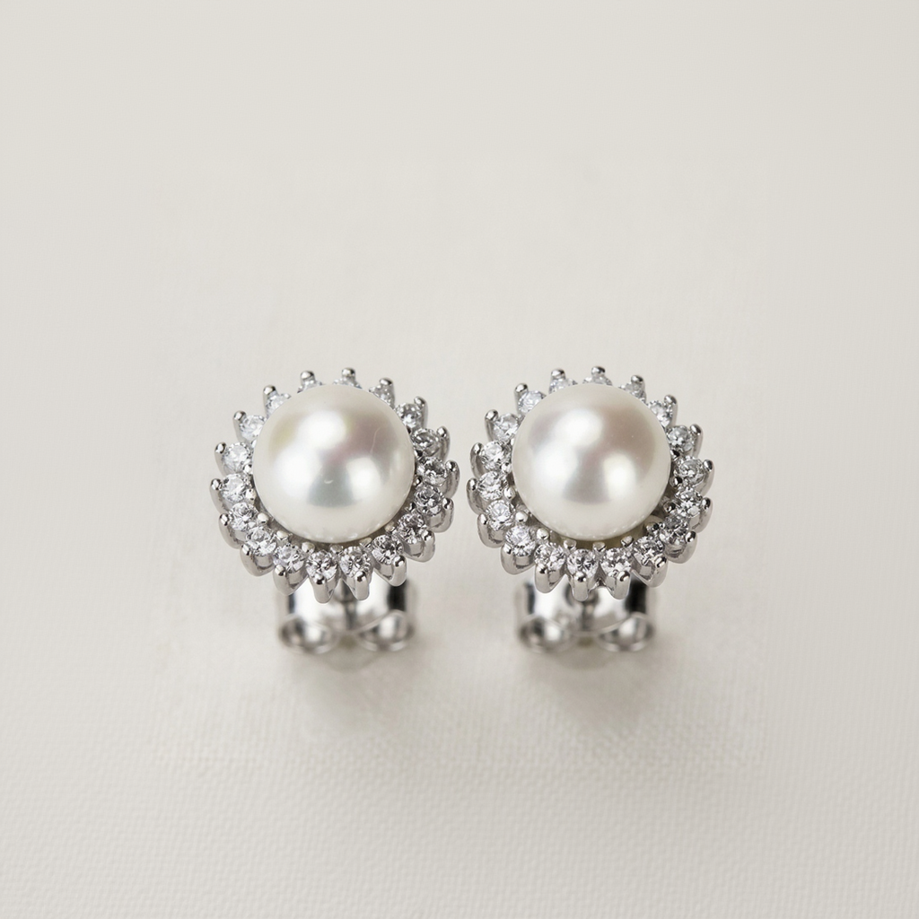 Pearl earrings with silver and clear gemstone accents on a light background