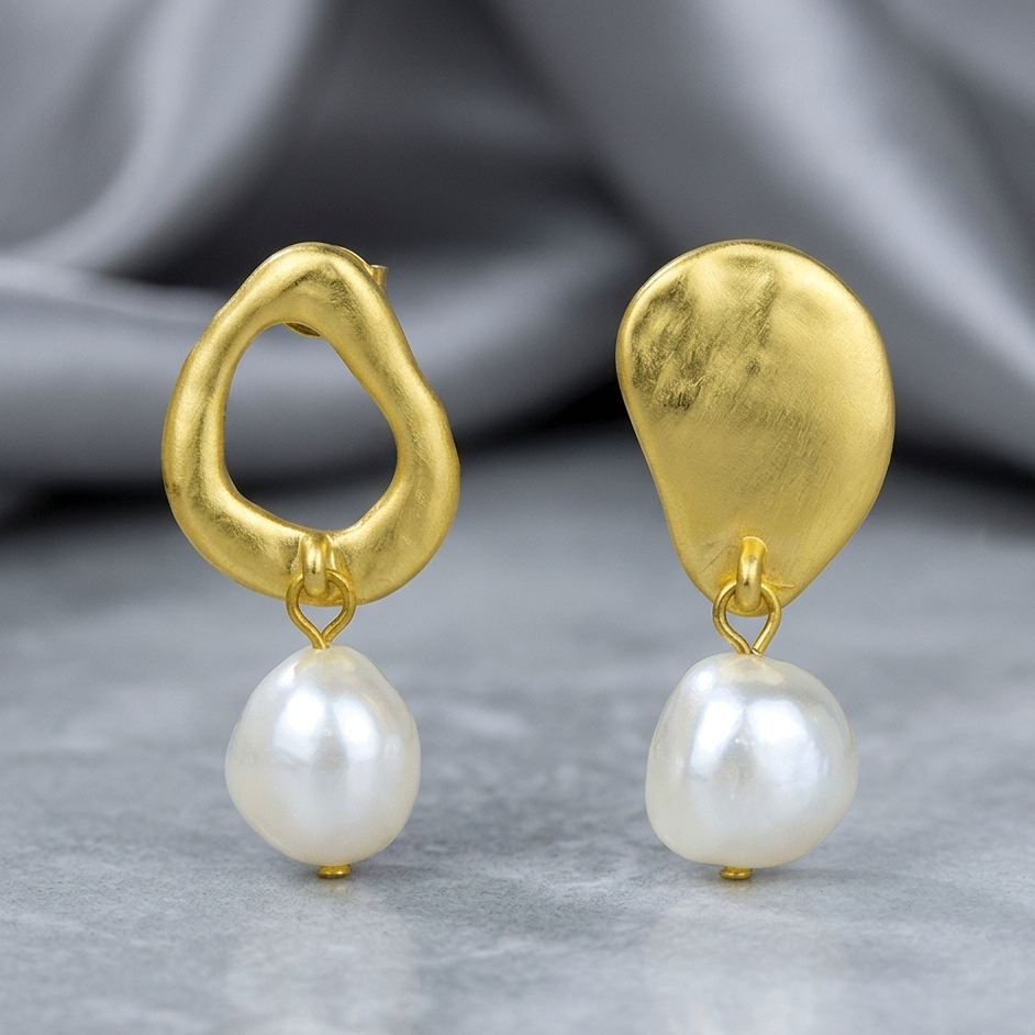 Gold earrings with pearl drops on a gray background