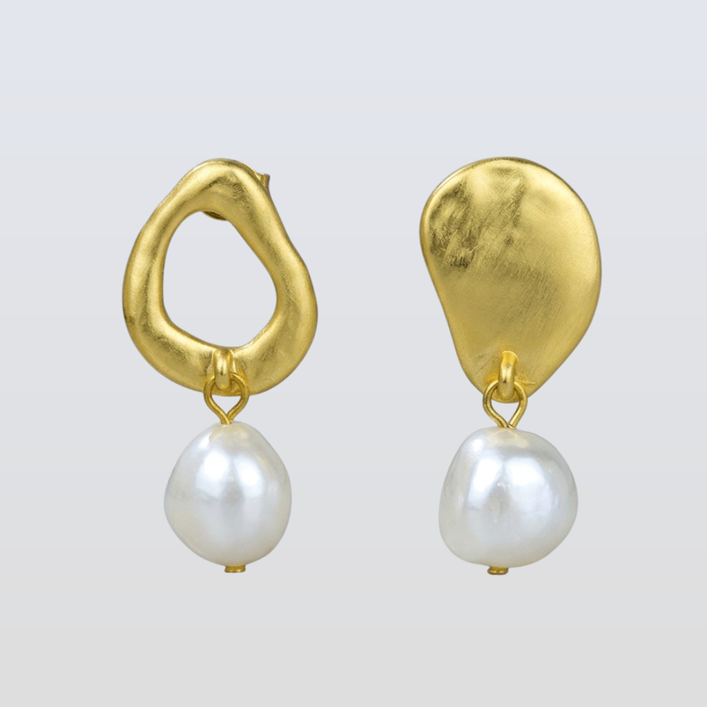 Gold earrings with pearl drops on a light gray background