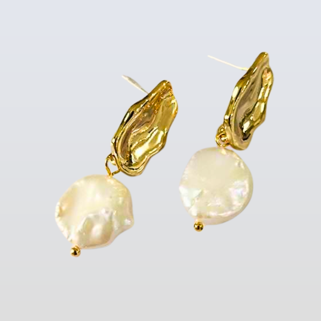 Gold earrings with pearl-like beads on a light gray background