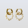 Gold hoop earrings with pearl beads on a light gray background