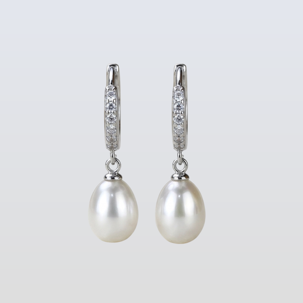 Pearl earrings with diamond accents on a light gray background