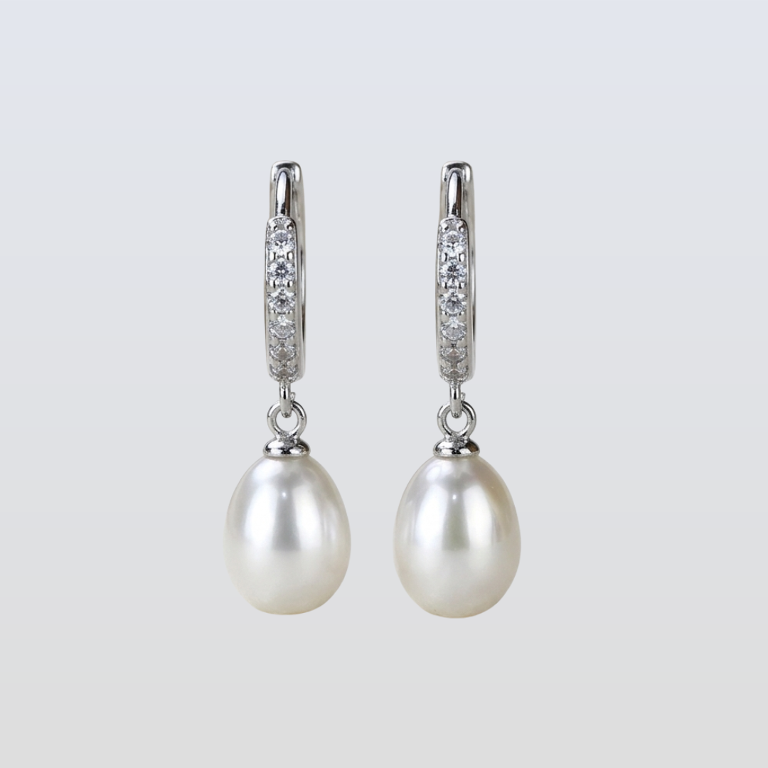 Pearl earrings with diamond accents on a light gray background