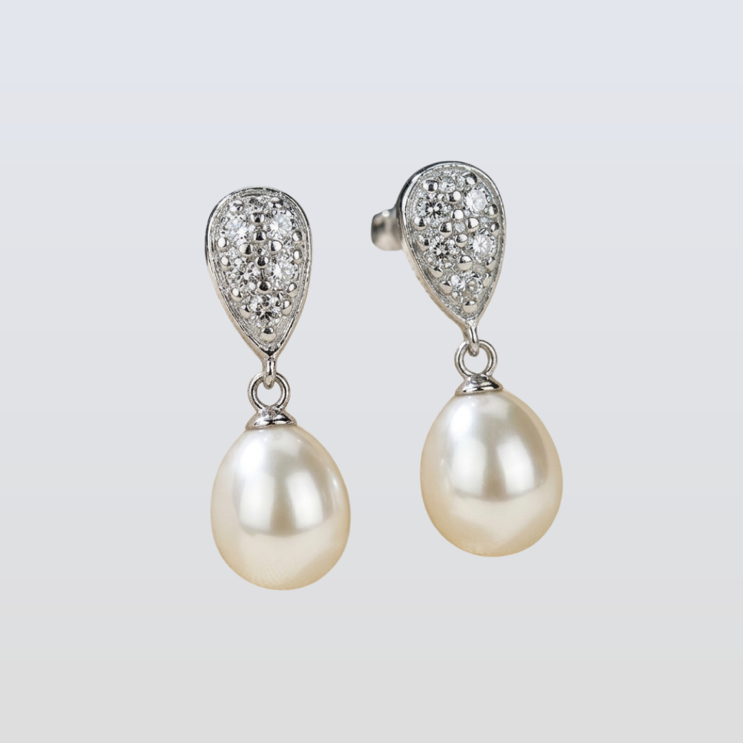 Pearl earrings with silver teardrop pendants on a light gray background