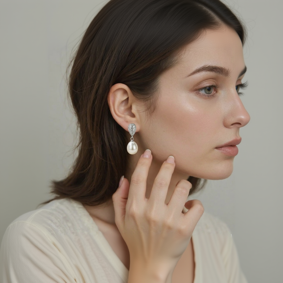 Close-up of a woman wearing a pearl earring with a neutral background