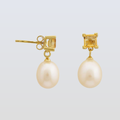 Gold earrings with pearl drops on a light gray background