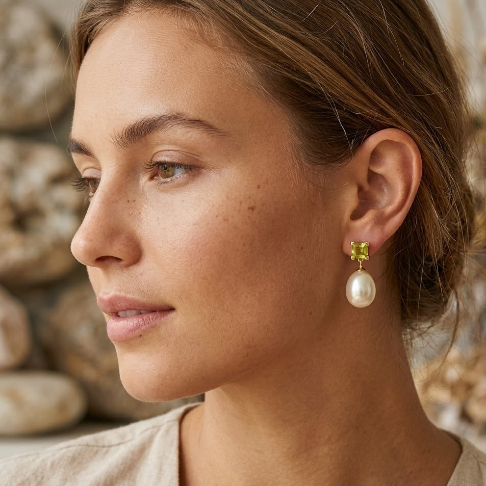 Close-up of a woman wearing pearl earrings with a blurred natural background