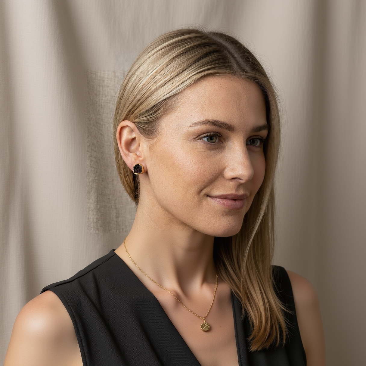 Close-up of a woman wearing a dark earring with a neutral background