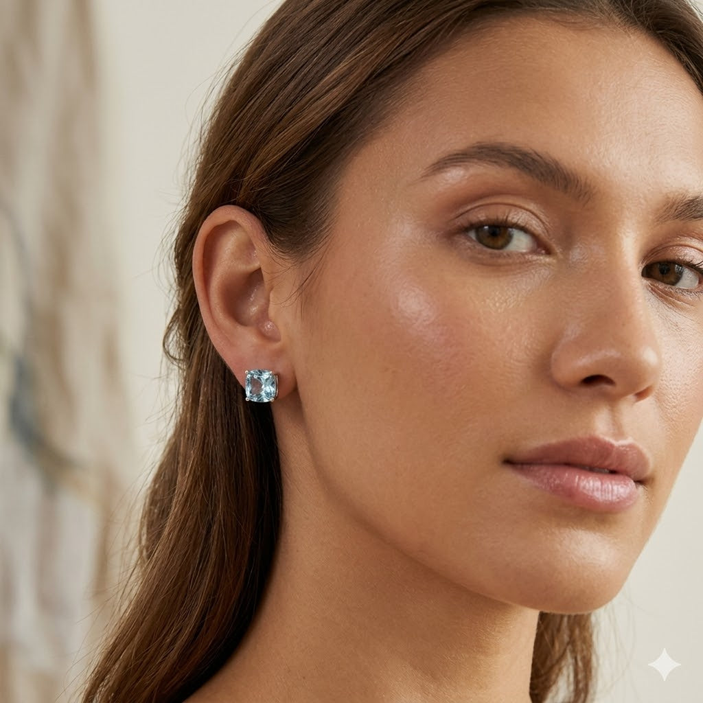 Close-up of a woman wearing a blue gemstone earring with a neutral background