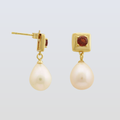 Pair of pearl earrings with gold and gemstone accents on a light gray background