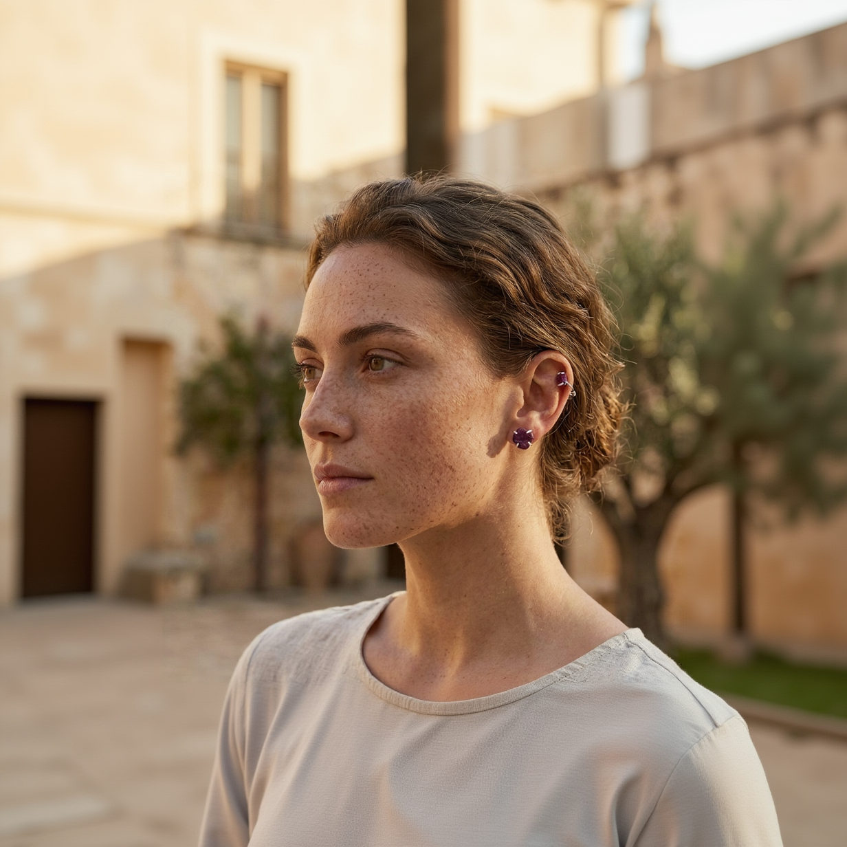 Woman wearing purple earrings outdoors with a blurred background